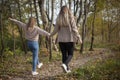 The girls are holding hands. Friends are walking in the autumn forest. Two girls happily walk through the park. Royalty Free Stock Photo