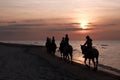 Girls horseriding on beach at sunset