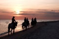 Girls horseriding on beach at sunset