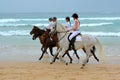 Girls and horses on beach ride