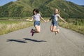 The girls jump on the road holding hands