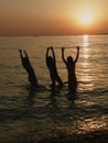 Girls jumping in the sea in sunset Royalty Free Stock Photo