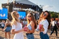 Girls laughing, dancing with cups at beach music festival. Group enjoys summer event, sunny seaside party atmosphere Royalty Free Stock Photo