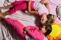 Girls lie on white and pink bed sheets bending Royalty Free Stock Photo