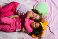 Girls lie on white and pink bed sheets hugging Royalty Free Stock Photo