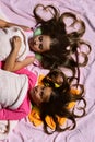 Girls lie on white and pink bed sheets Royalty Free Stock Photo