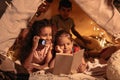 Girls with lighter reading book in handmade tent at home