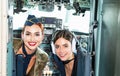 Girls looking at camera. Happy and successful flight. Back view from the inside of the plane. Women pilots smile and Royalty Free Stock Photo