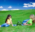 Girls in meadow with laptops Royalty Free Stock Photo