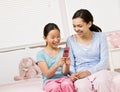 Girls in pajamas in bedroom text messaging Royalty Free Stock Photo