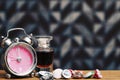 Girls pink alarm clock and small perfume bottle on the wooden table Royalty Free Stock Photo