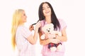 Girls in pink pajamas, isolated white background. Ladies on smiling faces with plush toy bear look cute. Girlish leisure