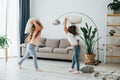 Girls are playing pillow fight game. Kids having fun in the domestic room at daytime together Royalty Free Stock Photo