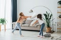 Girls are playing pillow fight game. Kids having fun in the domestic room at daytime together Royalty Free Stock Photo