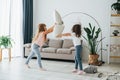 Girls are playing pillow fight game. Kids having fun in the domestic room at daytime together Royalty Free Stock Photo