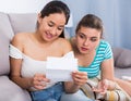 Girls reading billet-doux on sofa