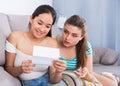 Girls reading billet-doux on sofa