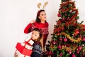 Joyful Girls with Reindeer Horns Surrounded by Gift Boxes and Christmas Tree