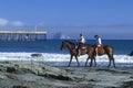 Girls riding horseback on beach, Morro Bay, CA