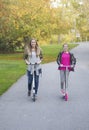 Girls riding their scooters in a city park together Royalty Free Stock Photo