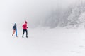 Girls running together on snow in winter mountains. Sport, fitness inspiration and motivation. Two women partners trail running in Royalty Free Stock Photo