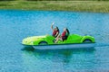 Girls in safety jackets wave and ride a pedal boat on a mountain lake Royalty Free Stock Photo