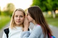 Girls schoolgirls teenagers, in summer in park, talking on the ear. The concept of secret, fantasy, thought. Emotions