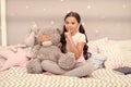 Girls secret. Cute kid show silence finger gesture. Little secret. Small girl play with teddy bear in bed. Keeping mouth Royalty Free Stock Photo