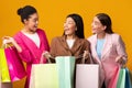 Three Happy Women Holding Shopper Bags Standing Over Yellow Background