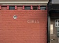 girls sign on red brick wall of ladies room in old building inside public park Royalty Free Stock Photo