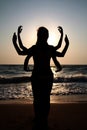 Girls silhouettes standing at the beach with arms raised up. Yog