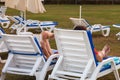 The girls sit in the sun loungers on the lawn on a summer day. Back view Royalty Free Stock Photo