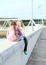 Girls sitting on railing of dam