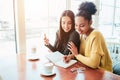 Girls sitting tigether very close to each other. One of them is writing something down in her notebook while the other Royalty Free Stock Photo