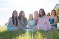 Girls Sitting Together in Grassy Field With Sunlight Overhead