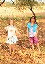 Girls standing barefoot under falling leaves