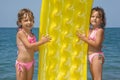Girls standing on beach with inflatable mattress Royalty Free Stock Photo