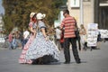 Girls street vendors in bright vintage dresses talking to the man selling their sweets from trays