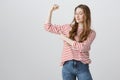 Girls are strong and powerful. Portrait of confident pretty caucasian girl raising arm with clenched fist, showing