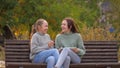 Girls students sitting in park on bench with a modern digital tablet. Teens from university, college, school, teach Royalty Free Stock Photo