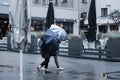 Girls take shelter with umbrellas from light rain and strong wind outside in bad weather