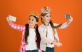 Girls taking selfie photo smartphone camera. Spoiled children concept. Egocentric princess. Kids wear golden crowns Royalty Free Stock Photo