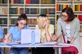 Girls teenage students studying in library with teacher mentor