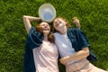 Girls teenagers having fun, lie on the green grass, laughing, to