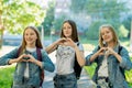 Girls teenagers in summer in the park in fresh air. Gesture hands show the heart of love. Dressed in casual clothes. The