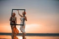 Girls traveler with wooden picture frame at colorful sea sunset