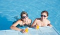 Girls in tropical pool with orange juice