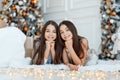 Girls twins in front of the fir-tree. New year`s eve. Christmas. Cozy holiday at the fir-tree with lights Royalty Free Stock Photo