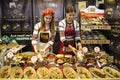 Girls in Latvian national dresses putting bread on a counter at a bakery store