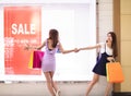 Girls watching discount poster and shopping in the mall